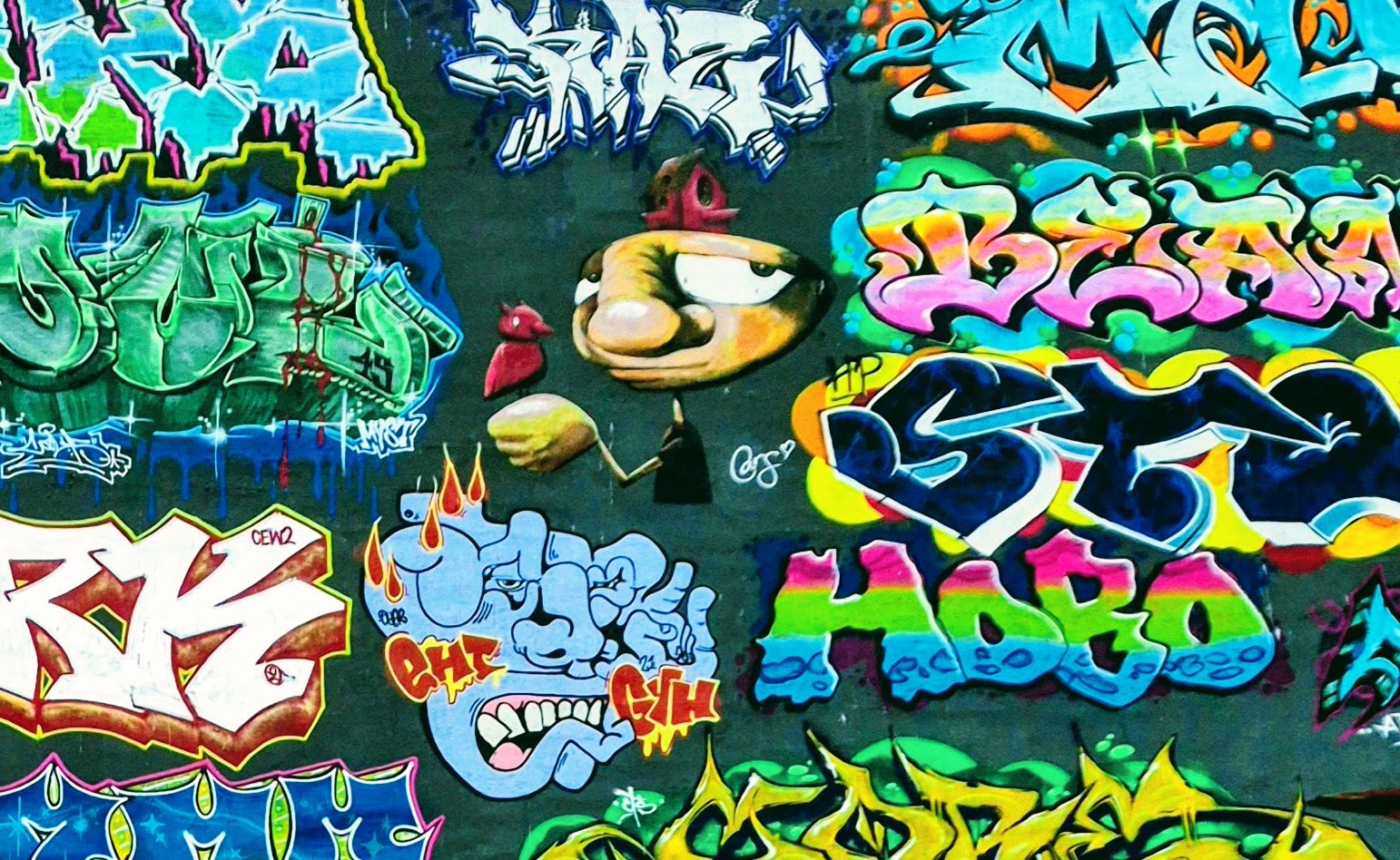 Close-up of overlapping graffiti tags in blue, pink and yellow